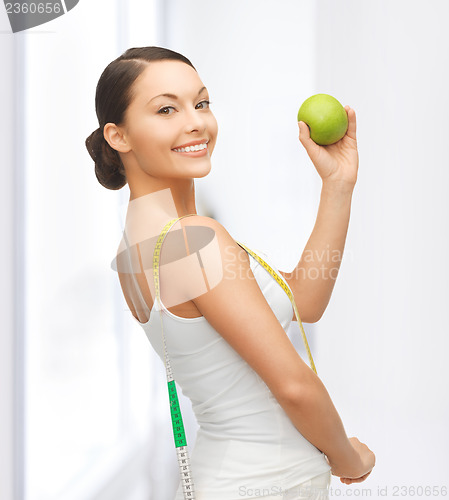 Image of sporty woman with apple and measuring tape