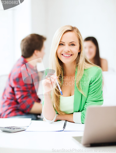 Image of smiling student girl with laptop at school