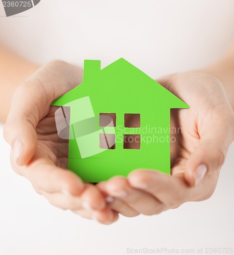 Image of woman hands holding green house