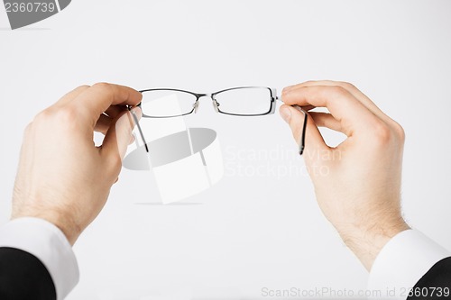 Image of man hands holding eyeglasses