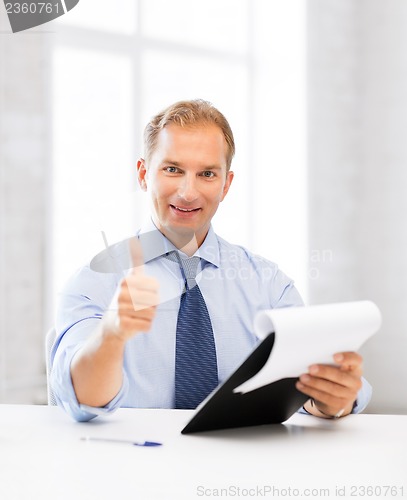 Image of businessman with papers showing thumbs up