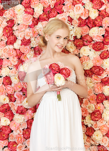 Image of woman with bouquet and background full of roses