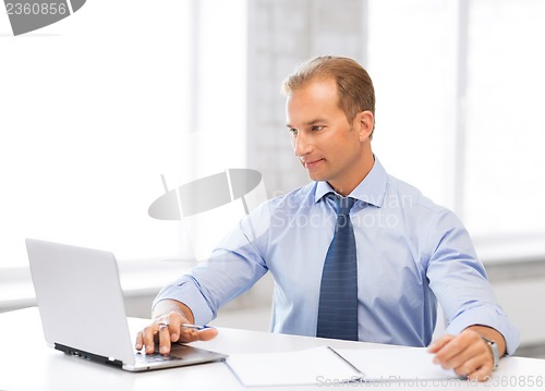 Image of miling businessman working in office