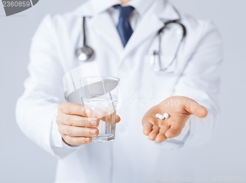 Image of doctor hands giving white pills and glass of water