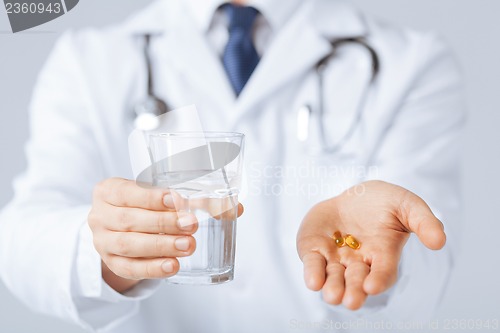 Image of doctor hands giving capsule and glass of water