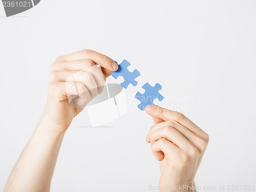 Image of two hands trying to connect puzzle pieces