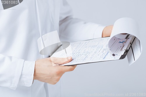 Image of male doctor holding prescription paper in hand