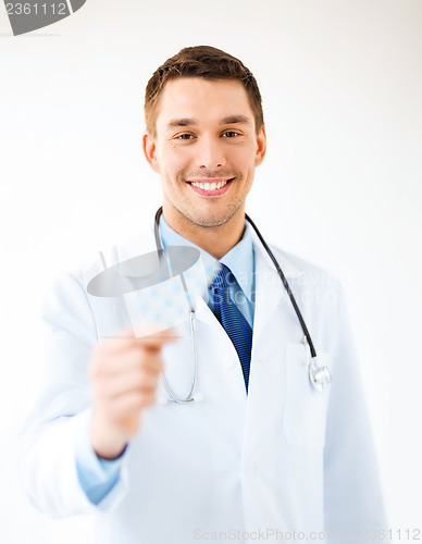 Image of young male doctor with pack of pills