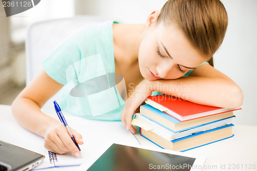 Image of tired student sleeping on stock of books