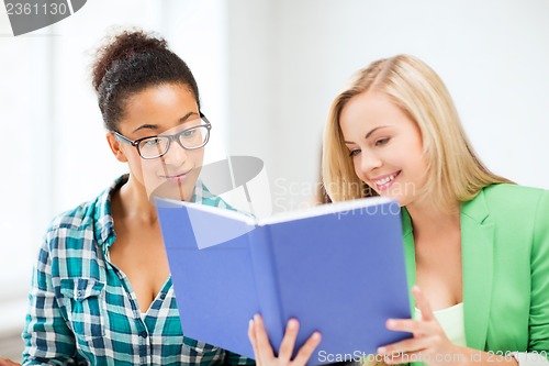 Image of smiling student girls reading book at school