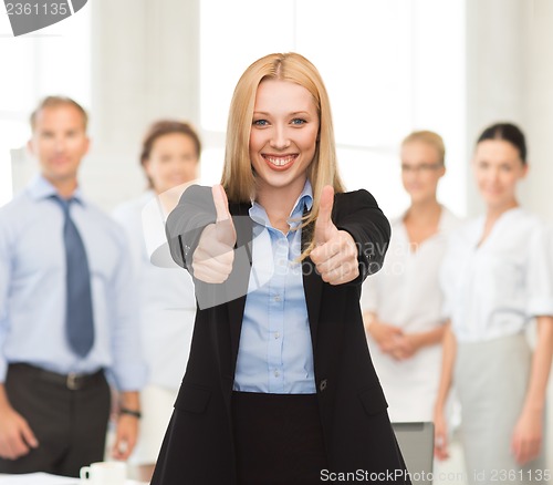 Image of businesswoman with thumbs up in office