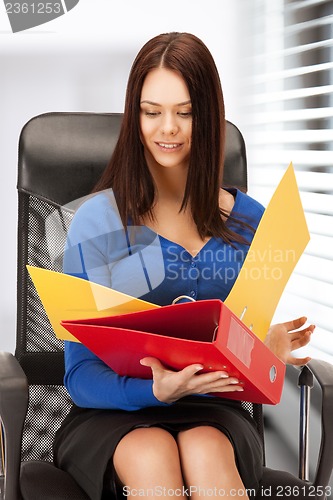 Image of young businesswoman with folders sitting in chair