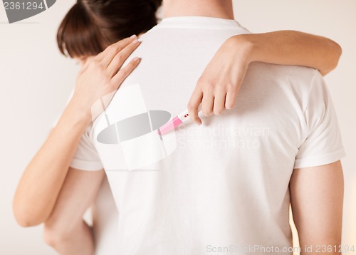 Image of woman with pregnancy test hugging man