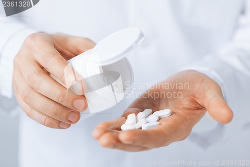 Image of doctor hands holding white pack and pills