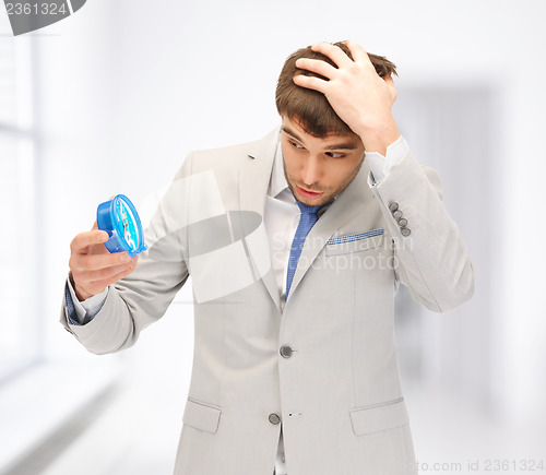 Image of handsome businessman looking at alarm clock