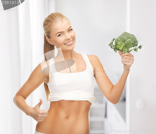 Image of woman pointing at her abs and holding broccoli