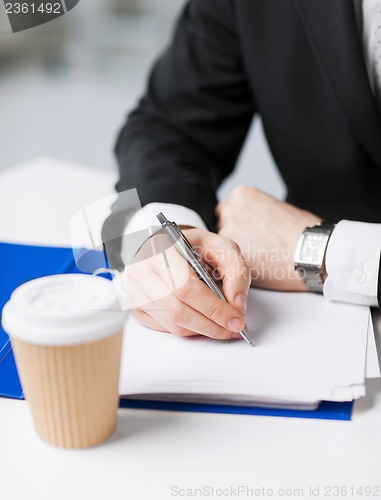 Image of businessman with coffee writing something