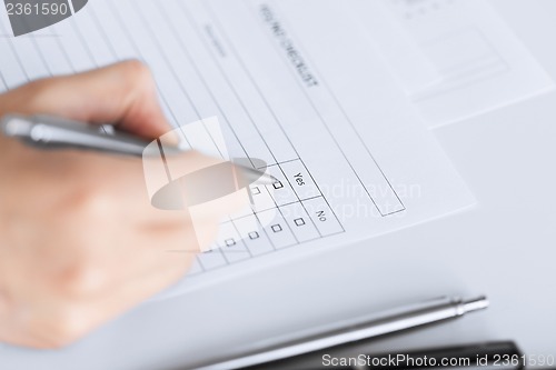 Image of woman hand with blank questionnaire or form