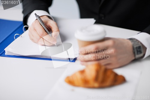 Image of businessman with coffee writing something