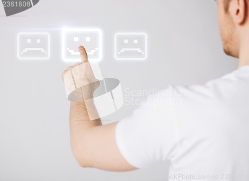 Image of hand touching virtual screen with smile button