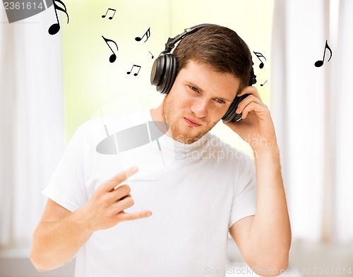 Image of man with headphones listening rock music at home