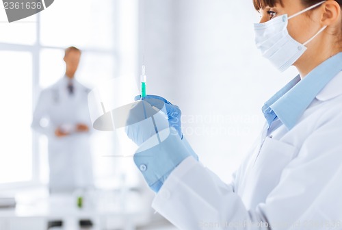 Image of female doctor holding syringe with injection