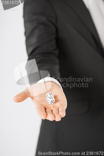 Image of mans hand holding white casino dice