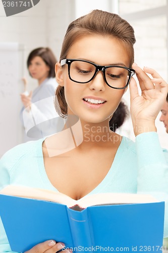 Image of smiling student girl reading book at school