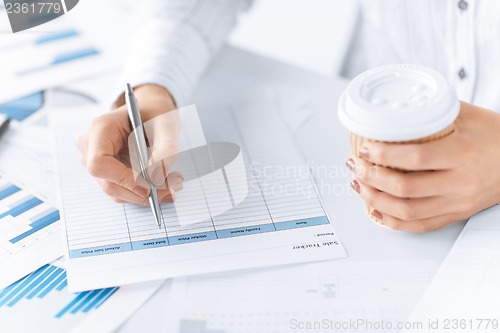 Image of woman filling in form and drinking coffee