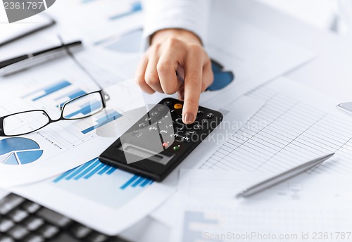 Image of woman hand with calculator and papers