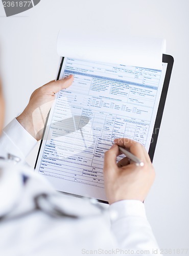 Image of male doctor holding prescription paper in hand