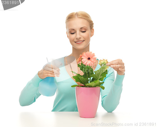 Image of woman holding pot with flower and spray bottle