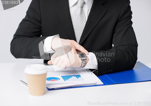 Image of businessman with graphs pointing at watch