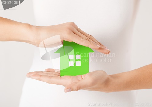 Image of woman hands holding green house