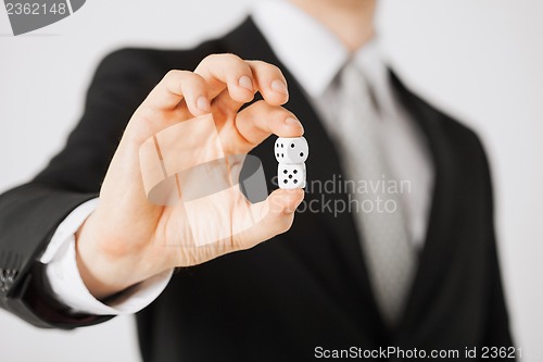 Image of mans hand holding white casino dice