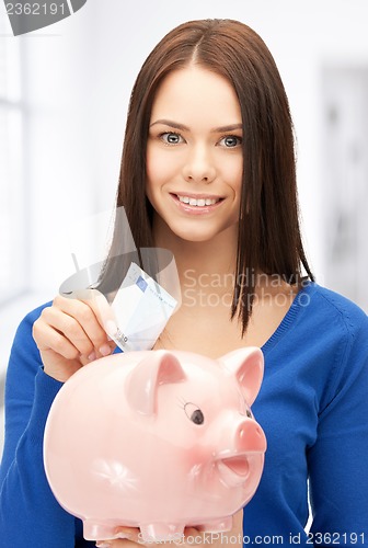 Image of lovely woman with piggy bank and money