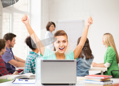 Image of happy student girl with laptop at school