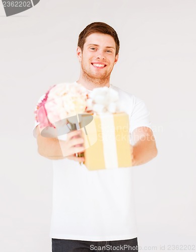 Image of man holding bouquet of flowers and gift box