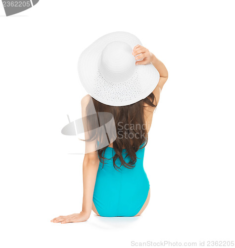 Image of model sitting in swimsuit with hat