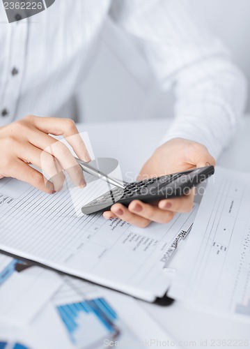 Image of woman hand with calculator and papers