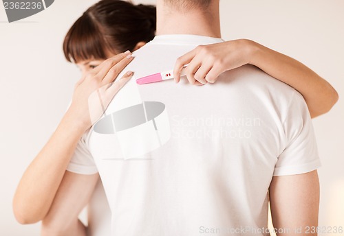 Image of woman with pregnancy test hugging man