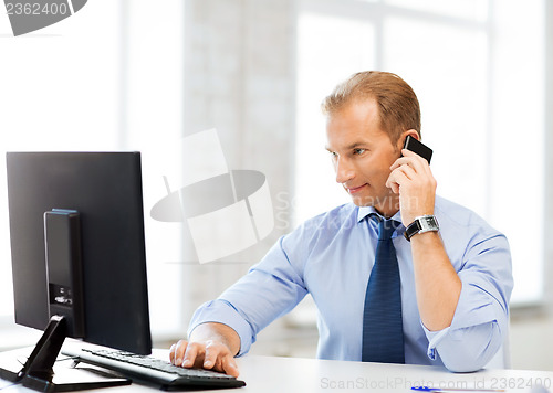 Image of smiling businessman with smartphone in office