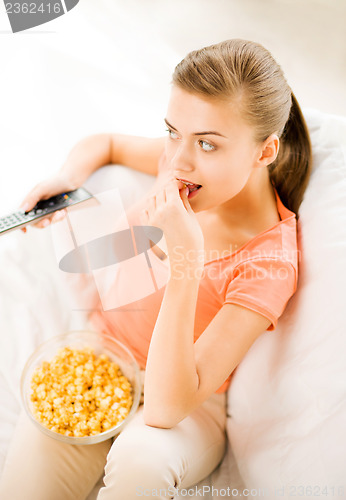 Image of woman watching tv and eating popcorn
