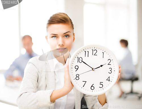 Image of businesswoman showing white clock in office