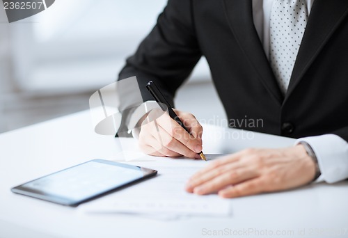 Image of man with tablet pc signing paper