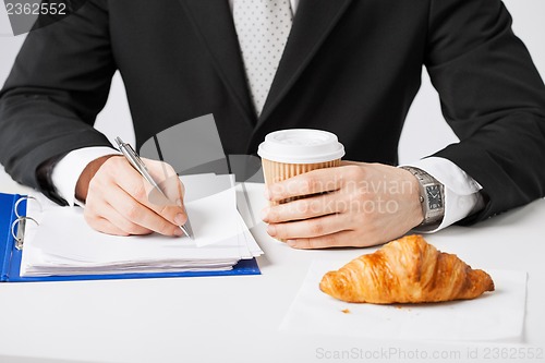 Image of businessman with coffee writing something