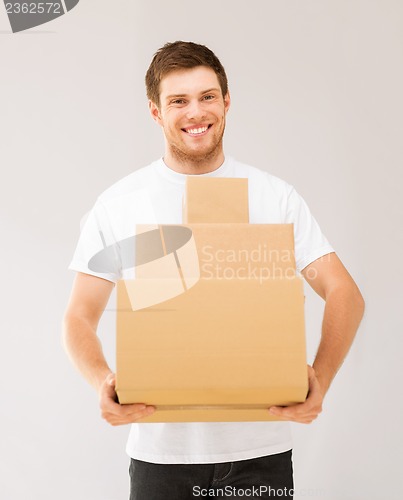Image of smiling man carrying carton boxes