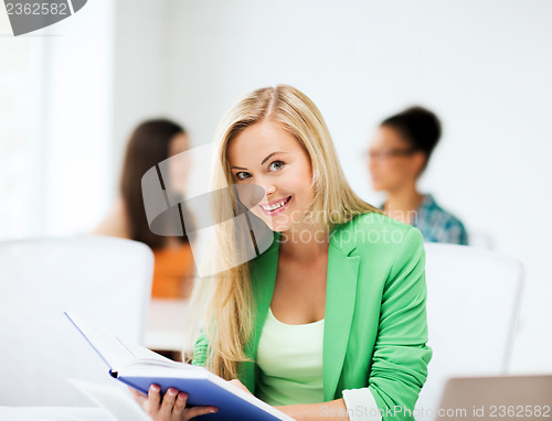 Image of smiling student girl reading book at school
