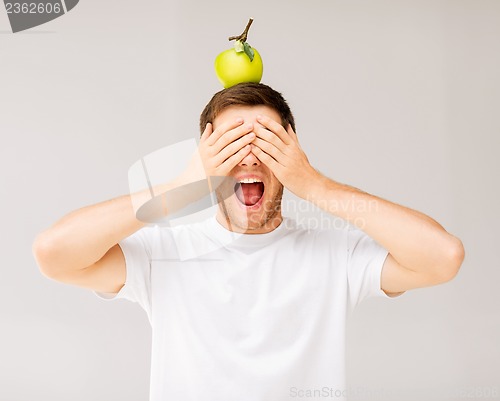 Image of man with green apple on his head