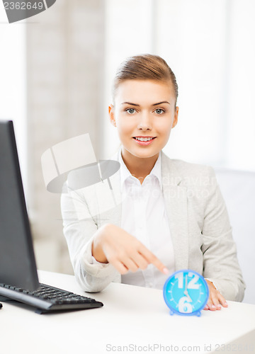 Image of attractive businesswoman pointing at clock